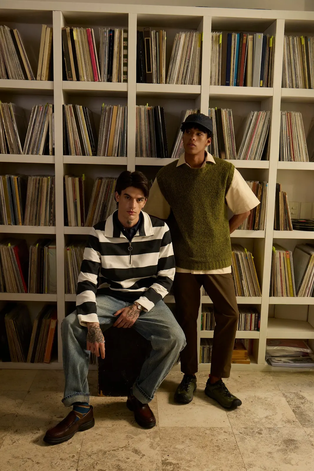 Two people posing together in front of shelves filled with vinyl records
